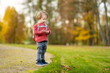 Komik çocuk güneşli bir sonbahar gününde dışarıda eğleniyor. Doğayı keşfeden çocuk. Şehir parkında oynayan bir çocuk. Küçük çocuklar için sonbahar aktiviteleri.