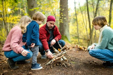 Baba ve çocuklar şenlik ateşinde çubuklarda marşmelov kızartıyorlar. Çocuklar kamp ateşinde eğleniyor. Sonbahar ormanlarında çocuklarla kamp yapmak. Sonbaharda çocuklarla aile eğlencesi..