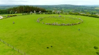 İrlanda 'nın Donegal İlçesi Raphoe kasabasının güneyinde bulunan ünlü Beltany taş çemberini keşfeden kadın turistin hava görüntüsü. M.Ö. 2100-700 yıllarından kalma..