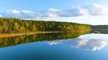Gela Gölü 'nün güzel yeşil sularının havadan görünüşü. Çam ormanlarıyla çevrili zümrüt göl manzaralı kuş bakışı. Litvanya 'nın Vilnius kenti yakınlarındaki Gela gölünde yansıyan bulutlar.