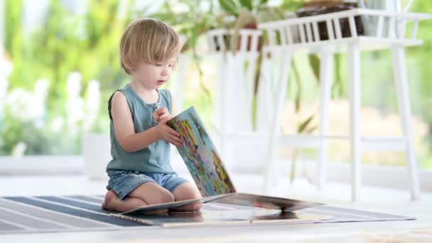 Filmagem Menino Bonito Lendo Livros Chão Casa Creche Atividade Criativa — Vídeo de Stock