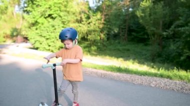 Yazın dışarıda bebek scooter 'ı süren komik çocuk. Şehir parkında bisiklete binen çocuk dengesi. Doğayı keşfeden çocuk. Küçük çocuklar için açık hava aktiviteleri. Yavaş çekim görüntüleri,