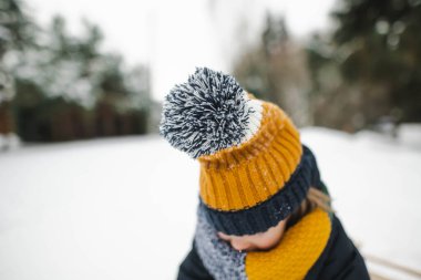 Tatlı çocuk serin kış günlerinde karla kaplı bir çam ormanında yürüyüş yaparken eğleniyor. Doğayı keşfeden çocuk. Küçük çocuklar için kış aktiviteleri.