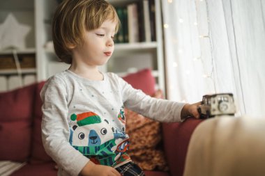 Oyuncak arabalarla oynayan tatlı çocuk. Küçük çocuk oyuncaklarla eğleniyor. Çocuk evdeki sıcak bir oturma odasında vakit geçiriyor. Evde aile eğlencesi..