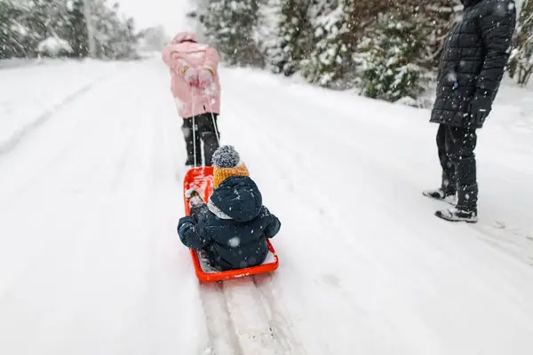 面白い幼児の少年と彼の大きな姉は 美しい冬の公園で寝て楽しんでいました 雪の中で遊んでいるかわいい子 子供のための冬の活動 — ストック写真