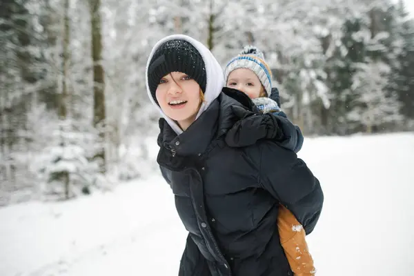 愛らしい幼児の少年と彼の姉は雪の冬の日に裏庭で楽しんでいました 雪の中で遊ぶ暖かい服を着ているかわいい子供 子供と家族のための冬の活動 — ストック写真
