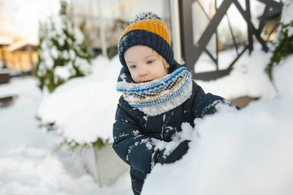 雪の降る冬の日に街で楽しんでいる愛らしい幼児の少年 雪の中で遊ぶ暖かい服を着ているかわいい子供 子供と家族のための冬の活動 — ストック写真
