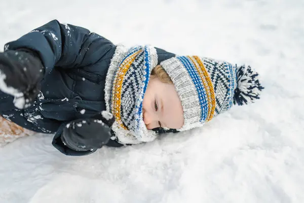 雪の冬の日に裏庭で楽しんでいる愛らしい幼児の少年 雪の中で遊ぶ暖かい服を着てかわいい子供 子供連れの家族のための冬の活動 — ストック写真