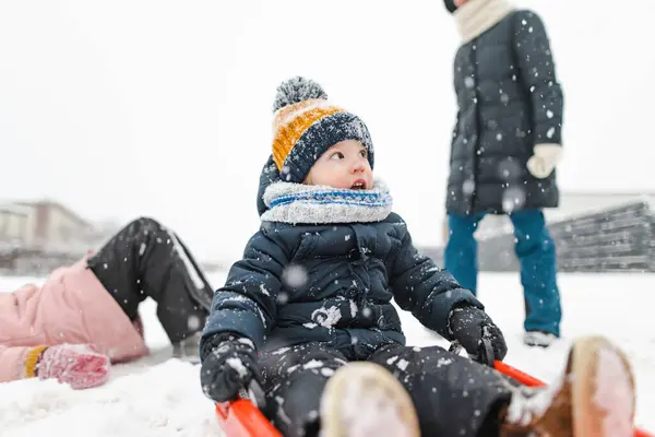 面白い幼児の少年と彼の大きな姉妹は 美しい冬の公園で眠って楽しんでいます 雪の中で遊んでいるかわいい子 子供のための冬の活動 — ストック写真