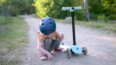 Yazın dışarıda bebek scooter 'ı süren komik çocuk. Şehir parkında bisiklete binen çocuk dengesi. Doğayı keşfeden çocuk. Küçük çocuklar için açık hava aktiviteleri. Yavaş çekim görüntüleri,
