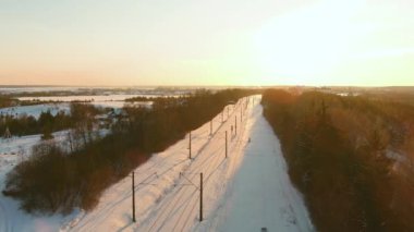 Kışın çam ormanları arasında bir demiryolunun hava günbatımı manzarası. Kış manzarası.