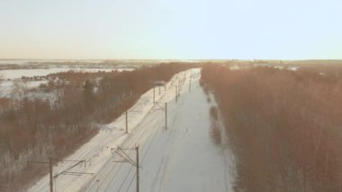 Kışın çam ormanları arasında bir demiryolunun hava günbatımı manzarası. Litvanya, Vilnius 'ta kış manzarası.