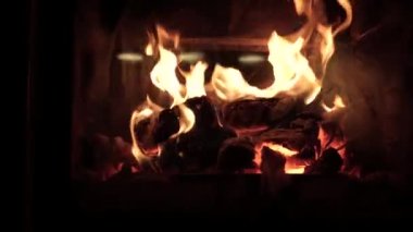 Taş şöminenin içinde yanan ateş kütükleri. Evde Noel tatili. Yanan ateş evi ısıtıyor. Sıcak ve sıcak bir oturma odası. Yakın çekim görünümü.