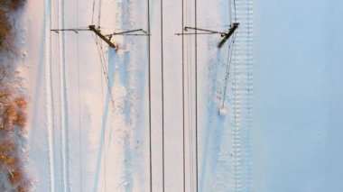 Kışın çam ormanları arasında bir demiryolunun yukarıdan aşağı gün batımı görüntüsü. Kış manzarası.