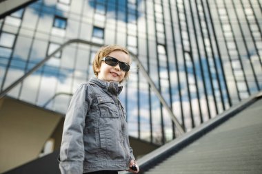 Neşeli küçük çocuk güneşli bahar gününde dışarıda eğleniyor. Şehirdeki çocuk. Şehir parkında oynayan bir çocuk. Çocuklu aileler için aktif eğlence.