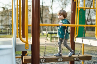 Küçük tatlı çocuk sıcak bir yaz gününde dışarıda oyun parkında eğleniyor. Yazın çocuklar için aktif eğlence.
