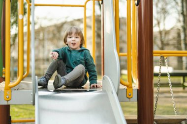Küçük tatlı çocuk sıcak bir yaz gününde dışarıda oyun parkında eğleniyor. Yazın çocuklar için aktif eğlence.