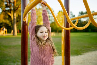 Güzel bir genç kız güzel bir yaz parkında oyun parkında eğleniyor. Yaz sonlarında dışarıda oynayan tatlı bir çocuk. Çocuklu aileler için açık hava aktiviteleri.