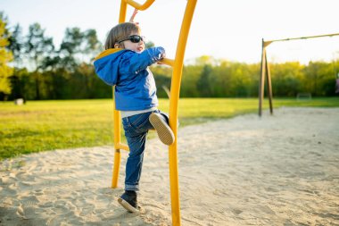 Ilık bahar gününde dışarıda oyun parkında eğlenen tatlı bir çocuk. İlkbaharda çocuklar için aktif eğlence.
