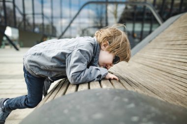 Neşeli küçük çocuk güneşli bahar gününde dışarıda eğleniyor. Şehirdeki çocuk. Şehir parkında oynayan bir çocuk. Çocuklu aileler için aktif eğlence.