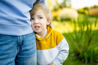 Sevimli komik çocuk annesine sarılıyor. Anne ve oğlu güneşli bir yaz gününde parkta eğleniyorlar. Sevimli oğlu annesi tarafından tutuluyor..