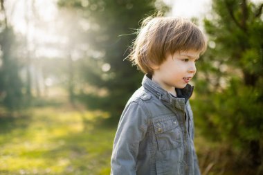 Güneşli bahar gününde dışarıda oynayan tatlı bir çocuk. Doğayı keşfeden çocuk. Küçük çocuklar için bahar etkinlikleri.