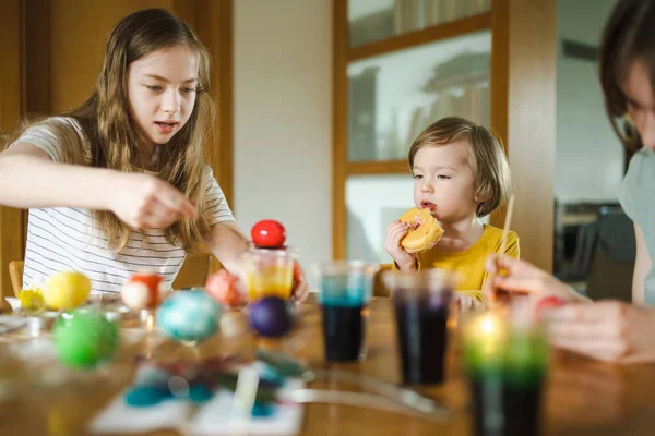 2人の姉妹と弟が家でイースターエッグを染めている イースターハントのためのカラフルな卵を描く子供たち 子供たちはイースターのお祝いの準備をしています ファミリーの伝統 — ストック写真