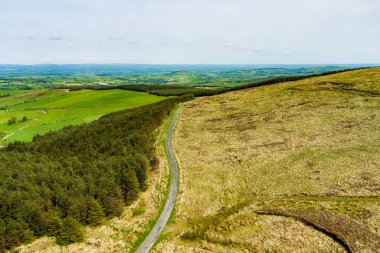 İrlanda'nın uçsuz bucaksız yemyeşil otlaklarının ve tarım arazilerinin havadan görünümü. Zümrüt yeşili alanlar ve çayırları ile güzel İrlandalı kırsal. Kırsal peyzaj.