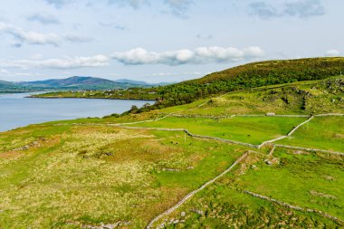 İrlanda'nın uçsuz bucaksız yemyeşil otlaklarının ve tarım arazilerinin havadan görünümü. Zümrüt yeşili alanlar ve çayırları ile güzel İrlandalı kırsal. Kırsal peyzaj.