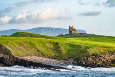Mullaghmore Head 'in pitoresk manzarasında ünlü Classiebawn Kalesi. Sahile vuran büyük dalgalarla muhteşem bir gün batımı manzarası. Wild Atlantic Way, Co. Sligo, İrlanda 'nın imza noktası