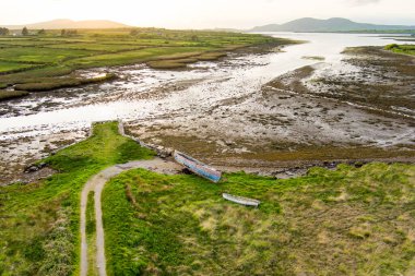 Eski tekne Kerry güzergahı Ring boyunca küçük bir plajda sol. Gün batımında Iveragh Yarımadası'nda Engebeli sahil, County Kerry, İrlanda.