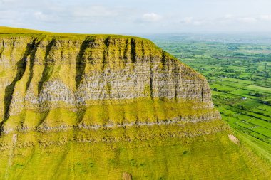 Aerial view of Benbulbin, aka Benbulben or Ben Bulben, iconic landmark, large flat-topped nunatak rock formation. Magnificent costal driving route view at Wild Atlantic Way, County Sligo, Ireland.