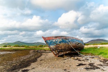 Eski tekne Kerry güzergahı Ring boyunca küçük bir plajda sol. Gün batımında Iveragh Yarımadası'nda Engebeli sahil, County Kerry, İrlanda.