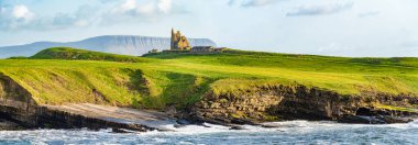 Mullaghmore Head 'in pitoresk manzarasında ünlü Classiebawn Kalesi. Sahile vuran büyük dalgalarla muhteşem bir gün batımı manzarası. Wild Atlantic Way, Co. Sligo, İrlanda 'nın imza noktası