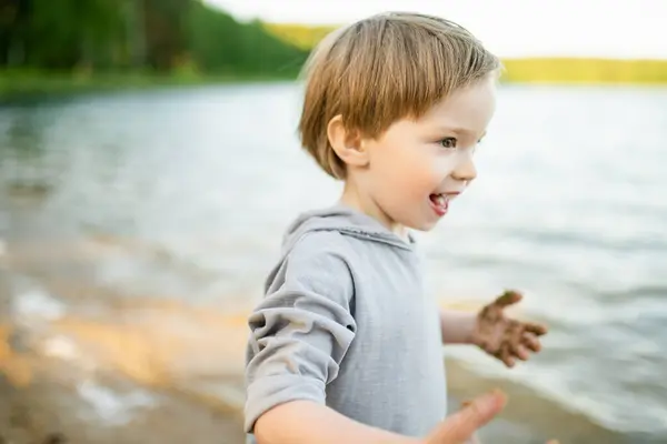 暑い夏の日に湖や川で遊んでいるかわいい少年 夏休みの間 アウトドアを楽しんでいる愛らしい子供 子供のための水の活動 ロイヤリティフリーのストック画像