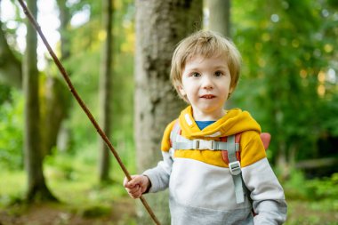 Sırt çantalı şirin bir çocuk güneşli bir yaz gününde dışarıda eğleniyor. Doğayı keşfeden çocuk. Çocuk seyahate çıkıyor. Çocuklu aileler için yaz etkinlikleri.