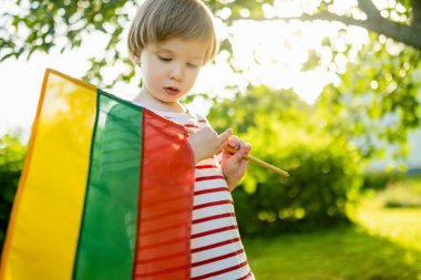 Cute little boy holding tricolor Lithuanian flag on Lithuanian Statehood Day, Vilnius, Lithuania clipart