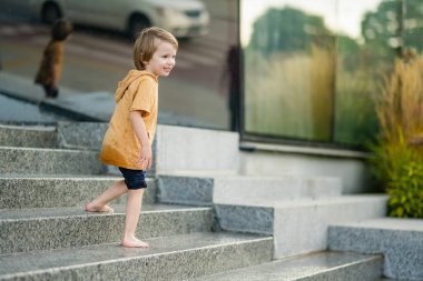 Küçük şirin çocuk şehir çeşmesinde suyla eğleniyor. Çocuk sıcak bir günde dışarıda su oyunu oynuyor. Küçük çocuklar için yaz etkinlikleri.