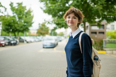 Ilık bir sonbahar sabahı okula giden sırt çantalı hoş bir genç kız. Çocuk okula geri dönüyor. Çocuklar için eğitim.