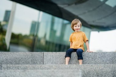 Neşeli küçük çocuk güneşli yaz gününde şehirde eğleniyor. Küçük çocuklar için açık hava yaz aktiviteleri.