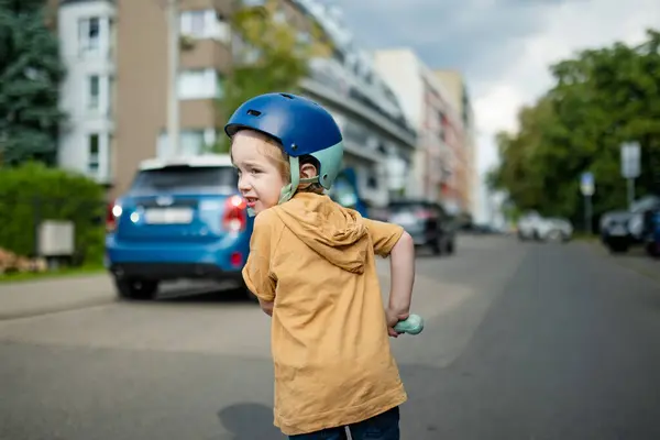 Adorable Tout Petit Garçon Chevauchant Son Scooter Dans Une Ville Image En Vente