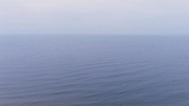 Mavi deniz su yüzeyinin havadan görünüşü. Dalgaların üzerinden uçmak. Sonsuz okyanus manzarası. Geniş su genişler. Bulutlu ya da sisli havada büyük bir vücut suyu. Bulutlu deniz manzarası.