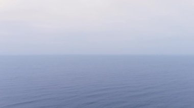 Mavi deniz su yüzeyinin havadan görünüşü. Dalgaların üzerinden uçmak. Sonsuz okyanus manzarası. Geniş su genişler. Bulutlu ya da sisli havada büyük bir vücut suyu. Bulutlu deniz manzarası.