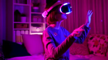 Karanlık bir odada sanal gerçeklik kulaklığı takan güzel bir genç kız. Oyun oynamak için VR gözlüğü kullanan sevimli bir genç. Sanal arttırılmış gerçeklik kaskındaki çocuk. Gelecekteki teknoloji konsepti.