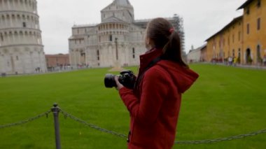 Genç bayan turist ünlü Eğik Pisa Kulesi 'nin fotoğraflarını çekiyor. İtalya 'da tatil, sezon dışı seyahat..