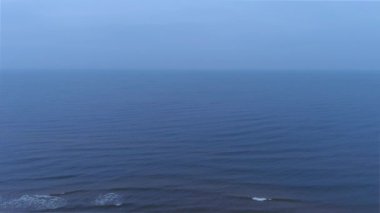 Mavi deniz su yüzeyinin havadan görünüşü. Dalgaların üzerinden uçmak. Sonsuz okyanus manzarası. Geniş su genişler. Bulutlu ya da sisli havada büyük bir vücut suyu. Bulutlu deniz manzarası.