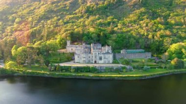 Gün batımında Kylemore Manastırı 'nda. Kylemore Kalesi 'nde kurulan bir Benedikt manastırı. Connemara güneşli yaz akşamı hava manzarası. İrlanda 'nın Galway ilçesinin ünlü turistik merkezi..