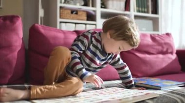 Güneşli bir öğleden sonra evdeki kanepede kitap okuyan tatlı çocuk. Gündüz kreşinde yaratıcı aktivite. Çocuklar eğleniyor. Eğitici öğrenme oyunları. Aile içi eğlence..