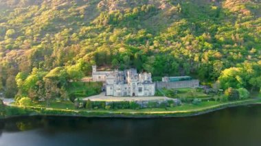 Gün batımında Kylemore Manastırı 'nda. Kylemore Kalesi 'nde kurulan bir Benedikt manastırı. Connemara güneşli yaz akşamı hava manzarası. İrlanda 'nın Galway ilçesinin ünlü turistik merkezi..