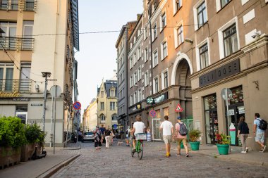 RIGA, LATVIA - 9 AĞUSTOS 2023: Kasaba halkı ve şehir misafirleri Riga 'daki renkli kaldırım taşlı caddelerde geziniyorlar. Letonya 'nın başkentinde canlı bir şehir hayatı.